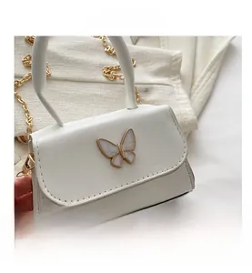 Close-up of white mini square bag featuring a gold-edged enamel butterfly and chain strap