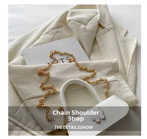 Detail shot of mini white square bag with golden chain strap and butterfly clasp decor