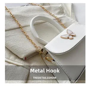 Close-up of white mini bag with elegant bow buckle and golden metal chain link strap