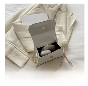 Detailed interior of mini white leather bag showing storage for earphones and compact powder