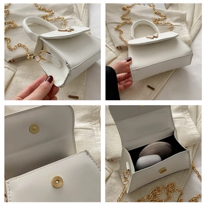 Detail view of mini white crossbody bag with golden butterfly buckle and chain strap