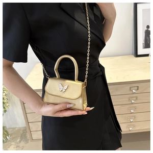 Mini gold crossbody bag featuring a white butterfly ornament and fine metallic chain strap