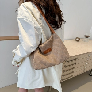 Grand sac cabas beige à carreaux avec fines bretelles en cuir marron porté à l'épaule