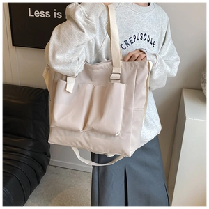 Detail of minimalist nylon tote bag with dual front pockets and adjustable shoulder strap