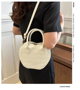 Macro shot of white apple-shaped bag featuring premium crocodile texture and gold hardware