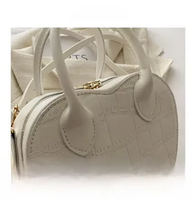 Detailed close-up of white crocodile embossed faux leather handbag with gold zipper