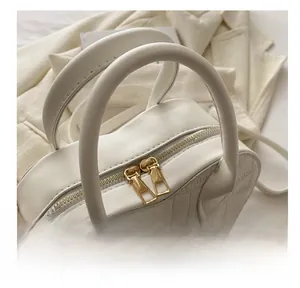 Close-up of white heart bag showing crocodile texture and gold double zippers