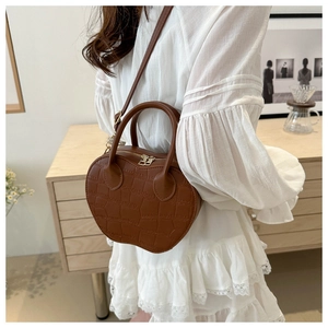 Detail of apple-shaped brown crossbody bag with crocodile texture and gold zippers