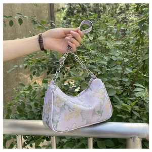 Detailed close-up of lavender fabric bag with gold floral embroidery and silver chain strap