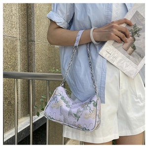 Detailed close-up of light purple embroidered handbag with floral landscape pattern