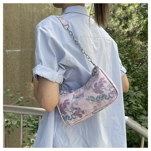 Close-up of pink jacquard fabric with nature pattern on shoulder bag with chain strap