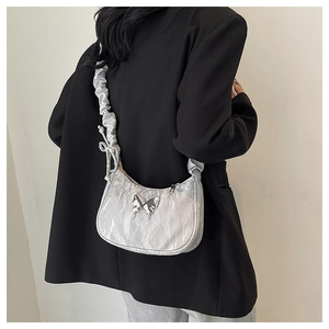 Detail of silver metallic crescent bag with butterfly hardware and ruched shoulder strap