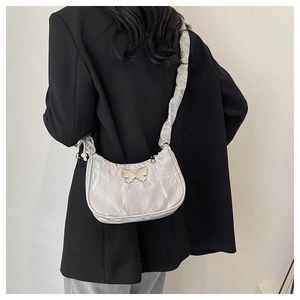 Détail du sac bandoulière argenté métallisé avec papillon et bandoulière plissée
