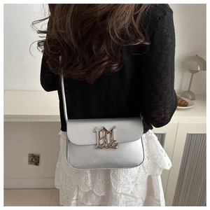 Detail of silver crossbody bag with HL gothic buckle worn by model against a white background