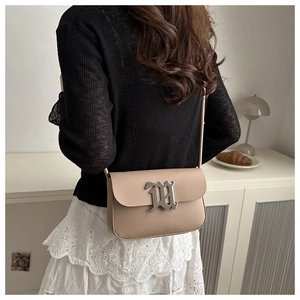 Detail of minimalist beige flap crossbody bag with gothic silver M metal buckle