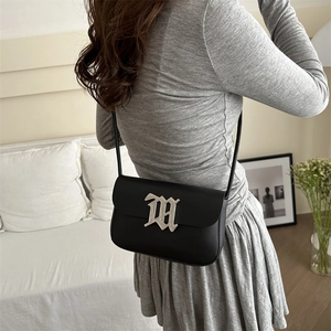 Minimalist black leather crossbody bag with vintage metal M buckle shown on model