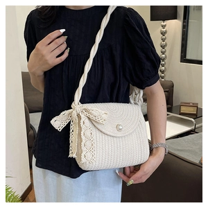Detail of cream straw bucket bag with pearl buckle and lace bow on a female model