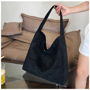 Detail of a large black suede tote bag showing soft texture and slouchy hobo design