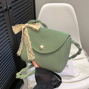 Women's green woven lace crossbody bag with large bow and pearl button detail