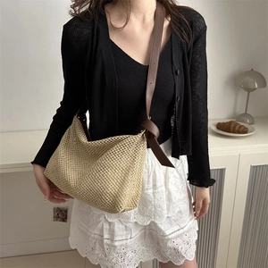 Minimalist beige woven tote bag with brown leather knotted strap worn by a model