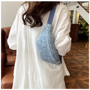 Detail of light blue floral embossed chest bag worn by model in a home setting