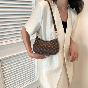 Brown monogram hobo bag with gold chain strap worn over a white silk blazer