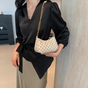 Beige crescent shoulder bag with geometric patterns and gold chain strap on model