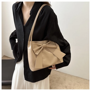 Détail d'un cabas beige élégant avec un grand nœud décoratif et une texture cuir mat