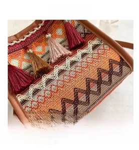 Dettaglio borsa a tracolla boho con nappe colorate e motivi geometrici in tessuto
