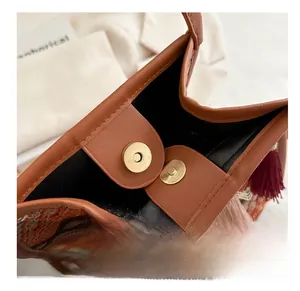Dettaglio della chiusura magnetica in metallo su borsa etnica intrecciata in pelle marrone