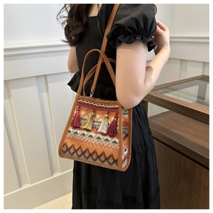 Dettaglio della borsa a secchiello boho con ricami geometrici, nappe colorate e manico in pelle