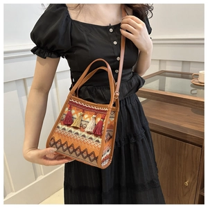 Dettaglio borsa etnica intrecciata con nappe colorate e tracolla in pelle