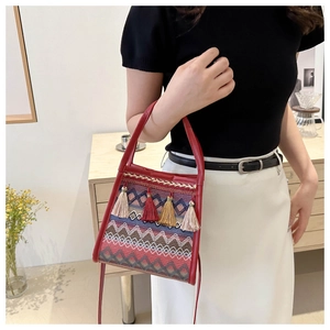 Dettaglio borsa a secchiello boho rossa con motivi geometrici e nappe colorate vivaci
