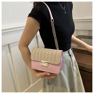 Detail of pink and woven crossbody bag with gold chain strap worn by a female model