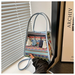 Dettaglio di trame geometriche e nappe colorate su questa borsa a secchiello etnica