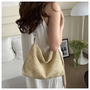 Close-up of woven straw tote bag featuring stylish metal chain strap and hobo design
