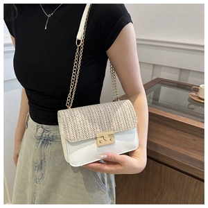 Detail of a straw woven crossbody bag with white leather, gold chain, and metal buckle