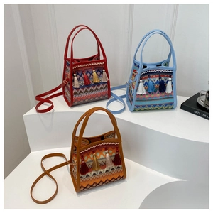 Dettaglio di borse a secchiello intrecciate boho con motivi e nappe colorate