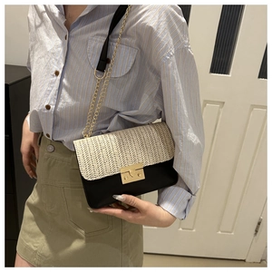 Detail of contrast stitching straw flap bag with golden chain strap on shoulder