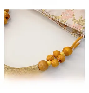 Detail of floral embroidery on brocade tote bag with beaded wooden handle and woven rope