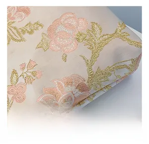 Macro detail of elegant pink satin fabric with intricate golden floral embroidery