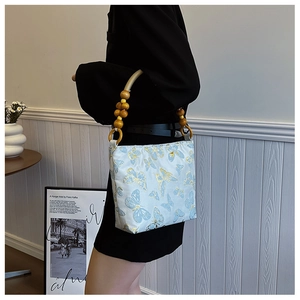 Light blue jacquard tote with golden butterfly patterns and a wooden bead handle
