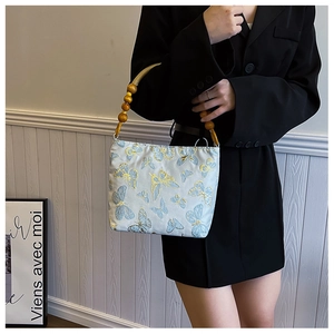 Detail of light blue satin bag with yellow butterfly embroidery and wooden bead handle