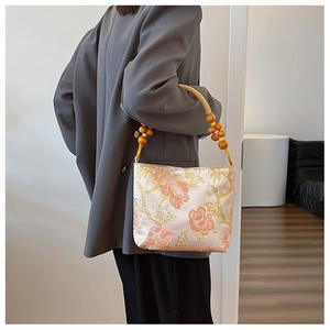 Detail of pink satin embroidery bag with floral patterns and wooden bead handle