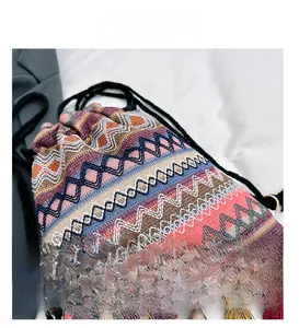 Dettaglio borsa a secchiello boho in maglia con motivi geometrici e nappe colorate
