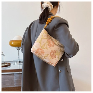 Detail of floral jacquard shoulder bag with decorative wooden beads and cord strap
