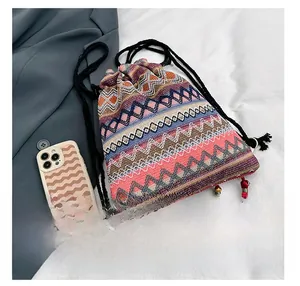 Dettaglio borsa a secchiello boho in maglia colorata con nappe e telefono per misura