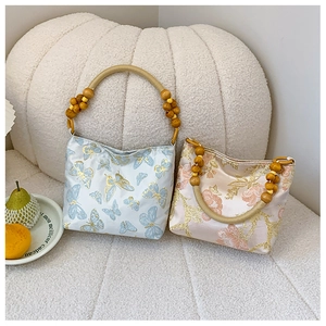 Detailed embroidery on vintage tote bags featuring wooden beaded handles and floral patterns