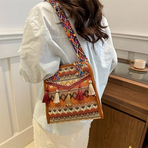 Detail of bohemian shoulder bag featuring ethnic woven patterns and colorful tassels
