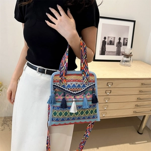 Close-up of bohemian woven shoulder bag with ethnic tassels and geometric patterns
